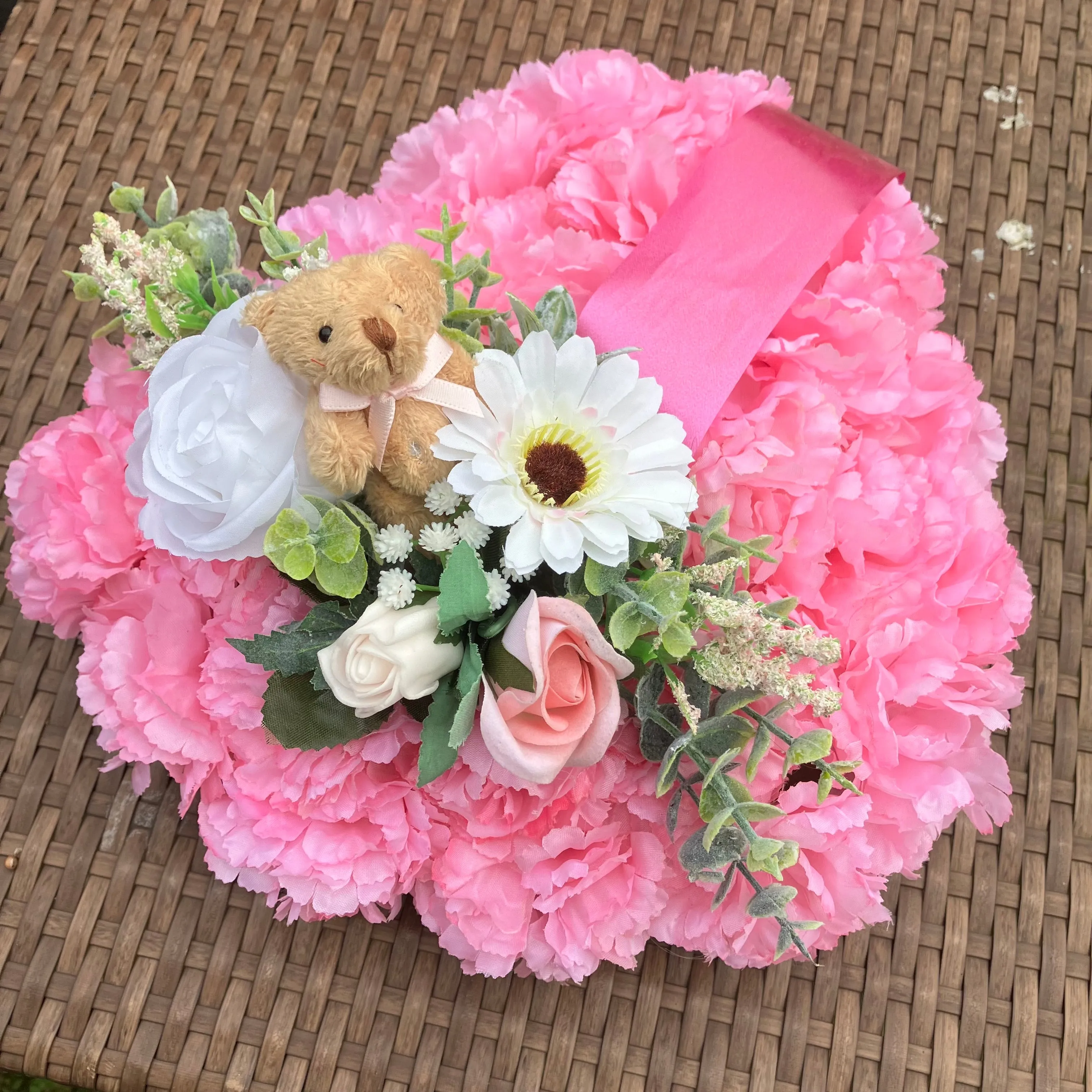 a memorial heart of artificial silk roses and carnations in shades of pink