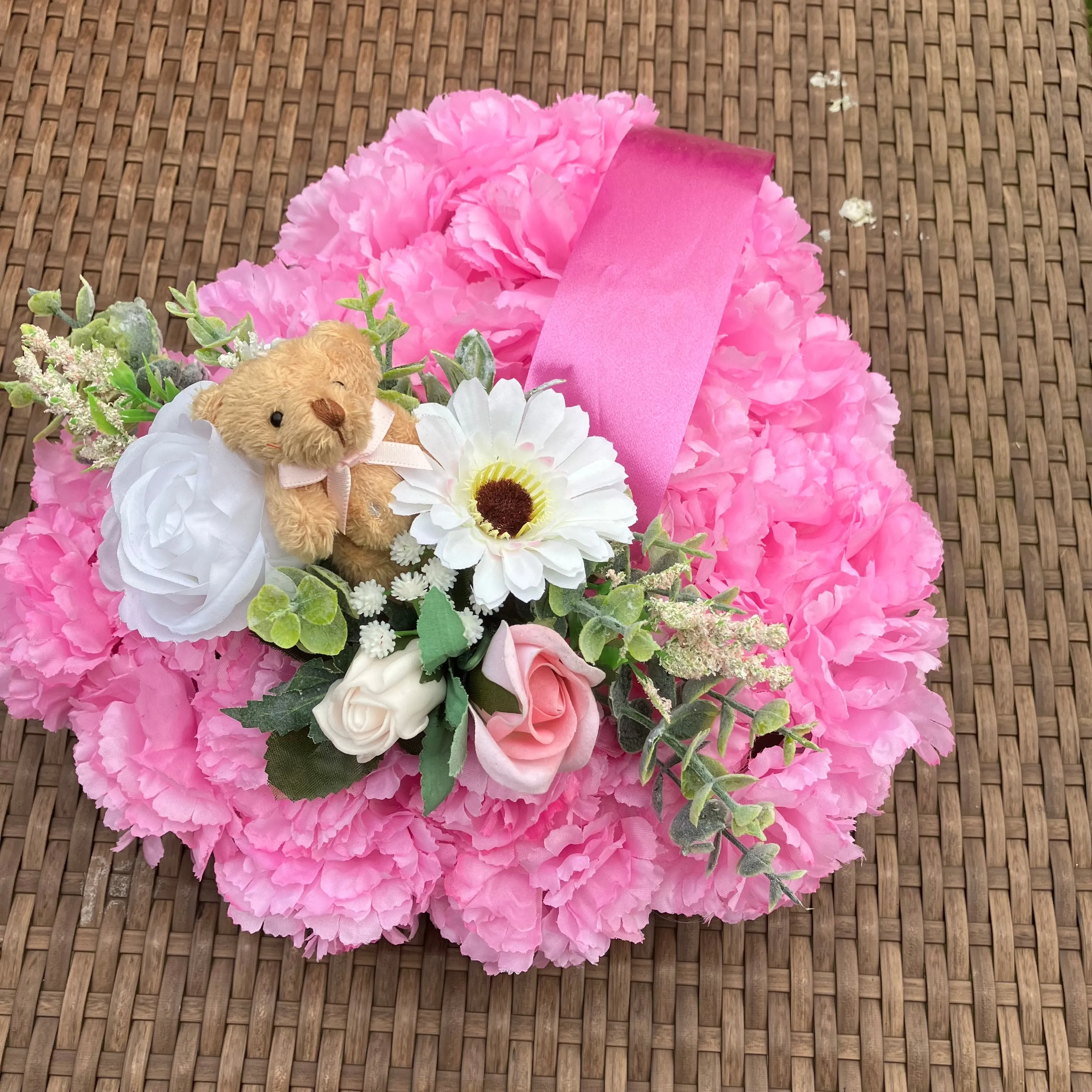 a memorial heart of artificial silk roses and carnations in shades of pink